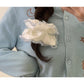 Satin white scrunchie with lace trim displayed on a wooden surface