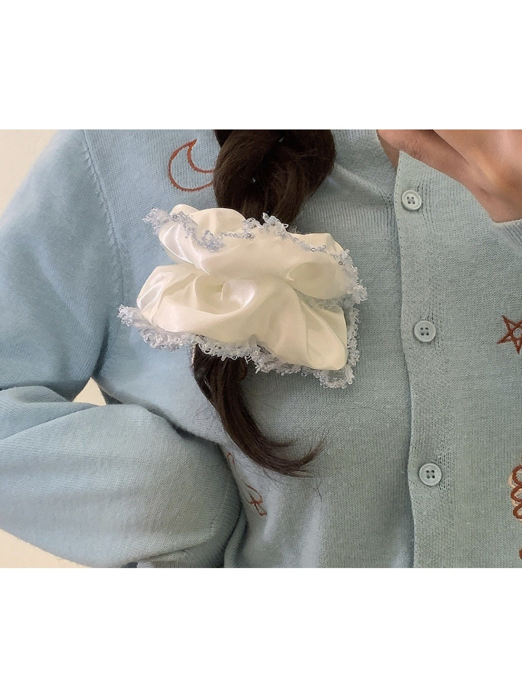 Satin white scrunchie with lace trim displayed on a wooden surface