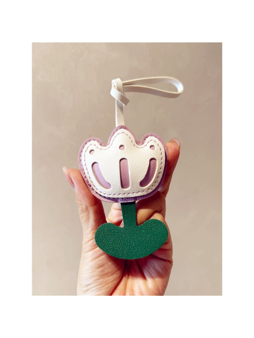 Hand holding the tulip-shaped keychain with a blurred background