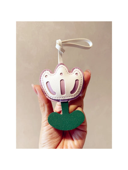 Hand holding the tulip-shaped keychain with a blurred background