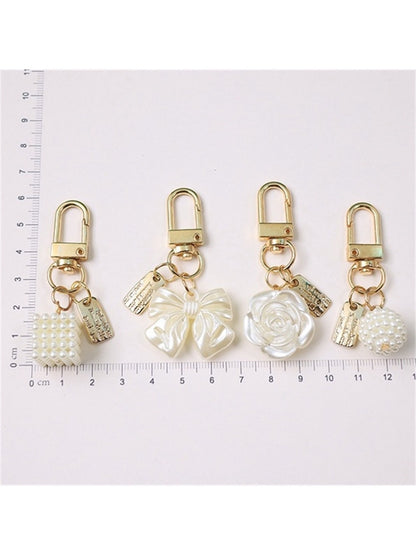 Keypus keychain featuring a pink beaded bow charm attached to a gold keyring on white background