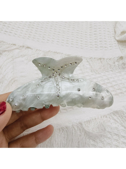 Beau rainbow claw clip resting on a white surface with natural lighting