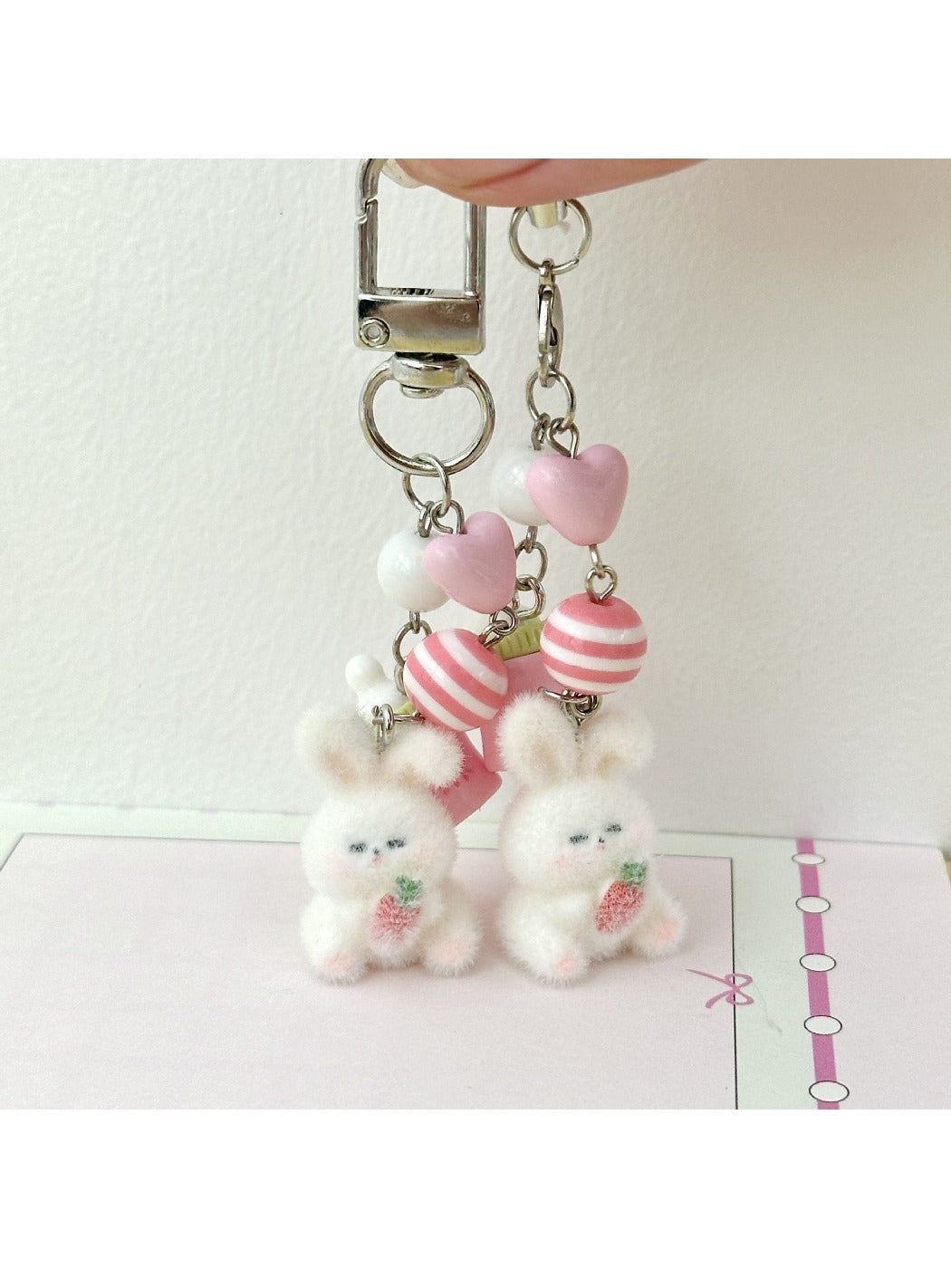 Pink bunny keychain hanging from a set of keys on a wooden surface