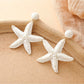Starfish drop earrings displayed with beach-themed props