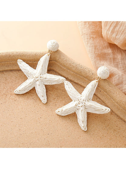 Starfish drop earrings displayed with beach-themed props