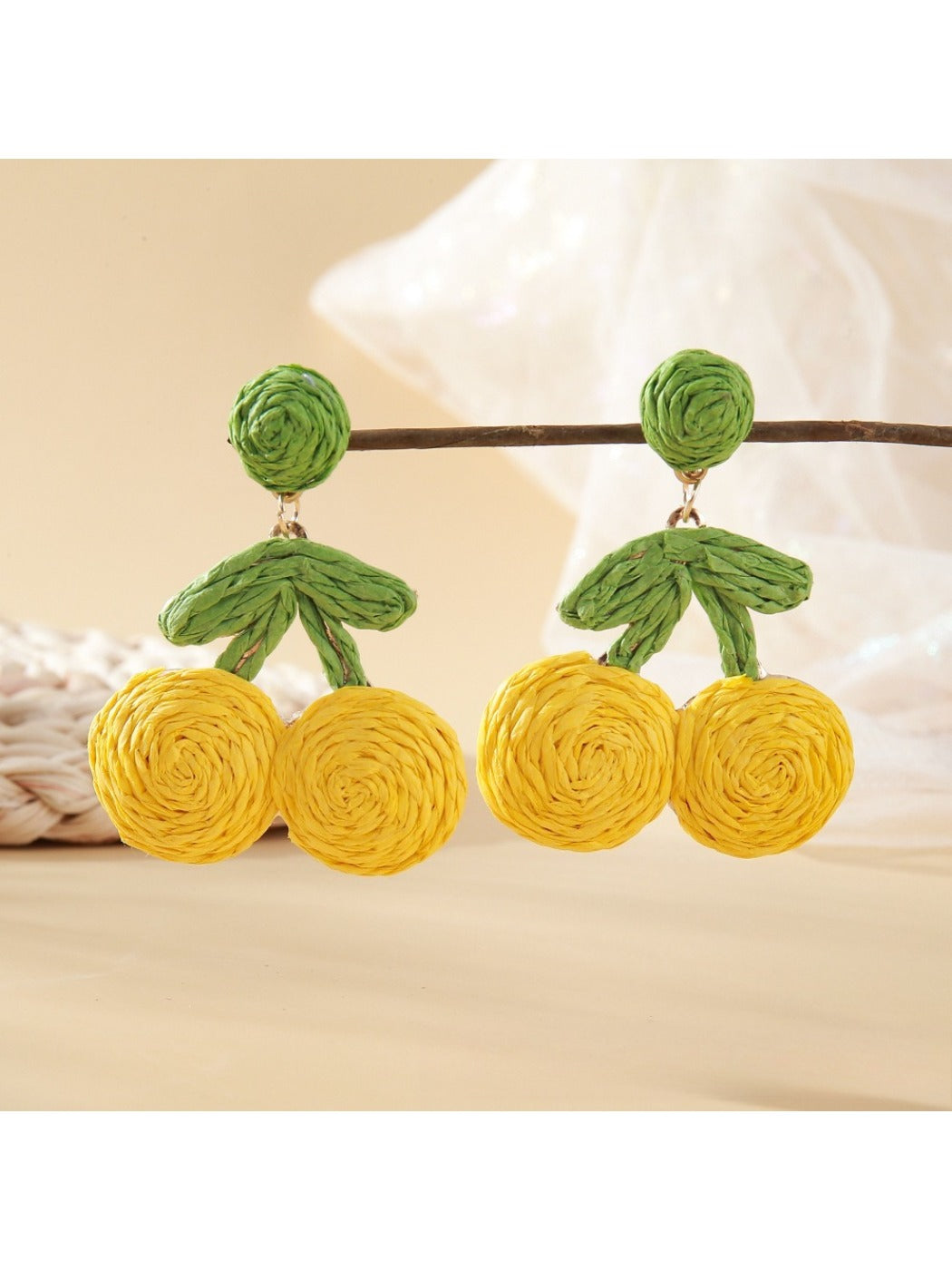 Earrings displayed hanging on a white card with raffia cherry design