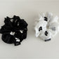 Close-up of Gifty scrunchie with gentle floral pattern on soft fabric