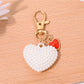 Heart shaped bag charm keychain displayed with matching red leather accessories
