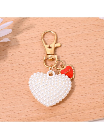 Heart shaped bag charm keychain displayed with matching red leather accessories