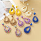 Close-up of Earedge hollow drop woven earrings in gold tone on white background