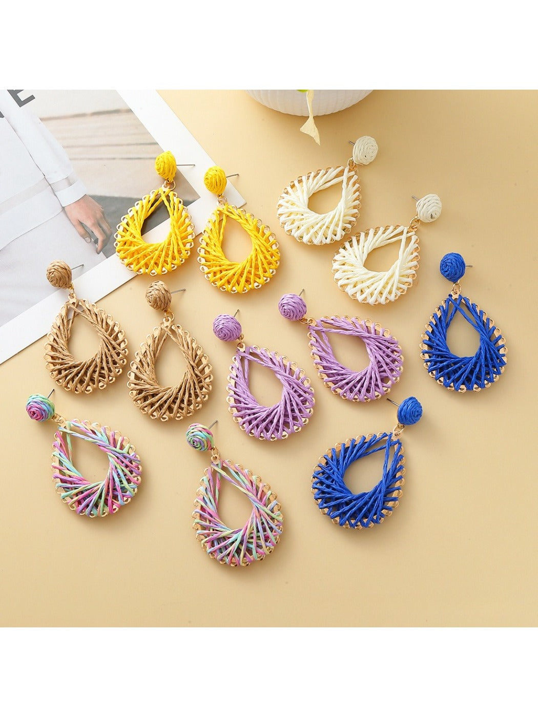 Close-up of Earedge hollow drop woven earrings in gold tone on white background
