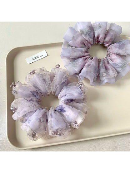 Purple printed scrunchie displayed on a white background showing fabric texture