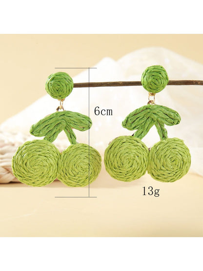 Side view of raffia cherry earrings showing woven texture and green leaf detail