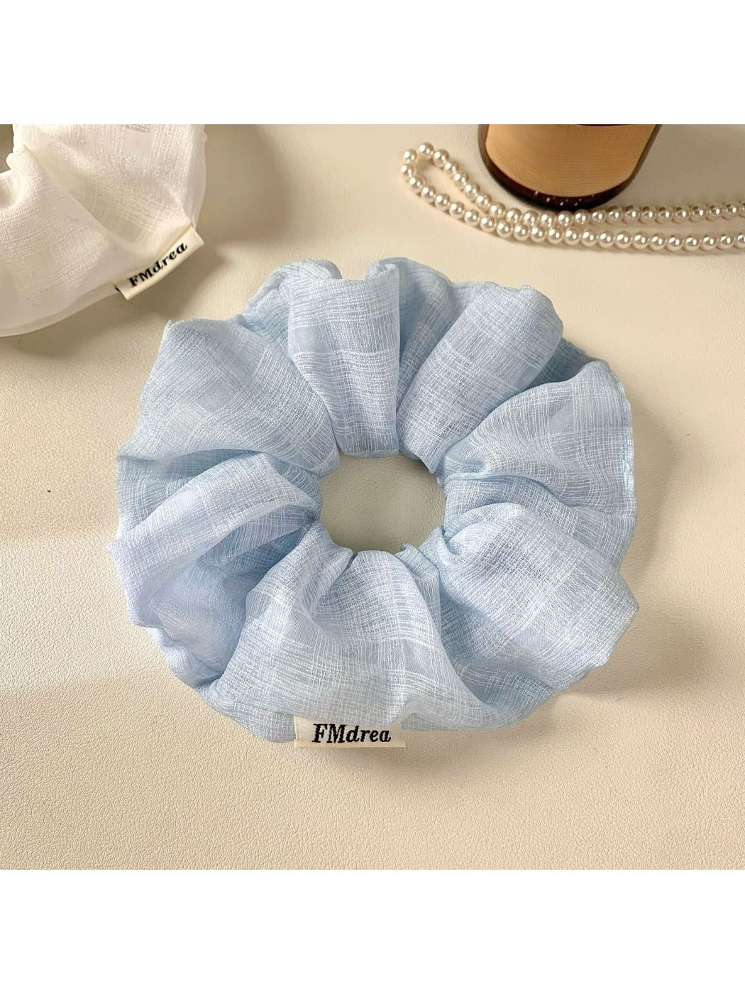 Top view of a solid color ruched scrunchie showing gathered fabric details