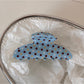 Blue polka dot hair clip displayed on a wooden surface