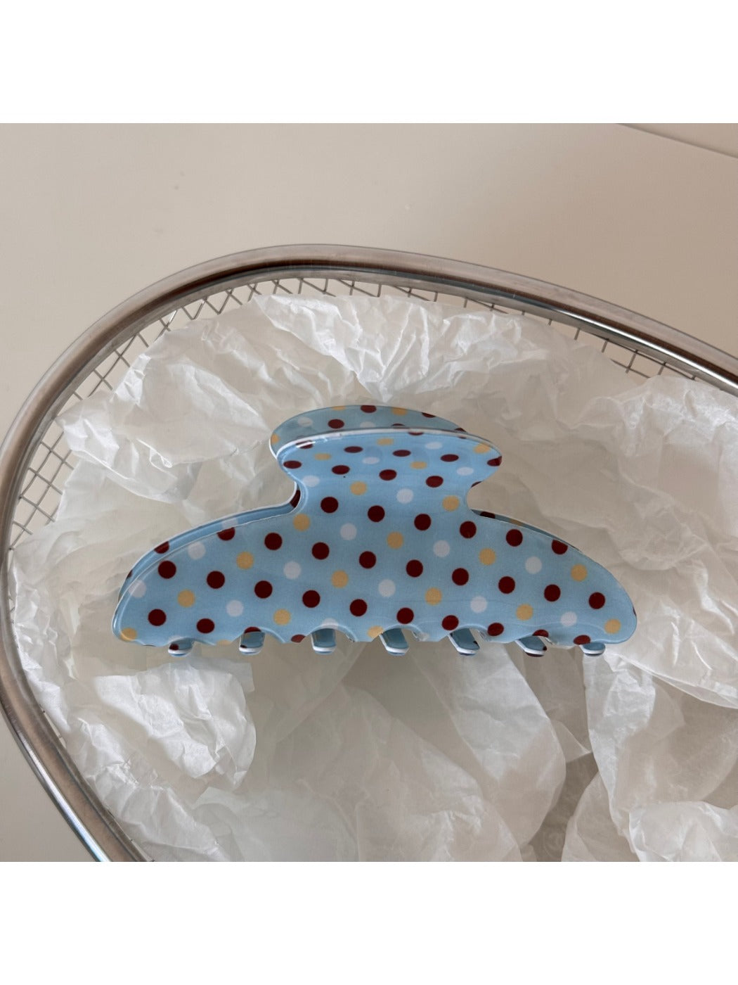 Blue polka dot hair clip displayed on a wooden surface