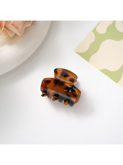 Beau hair clip placed on fabric surface highlighting texture and colors