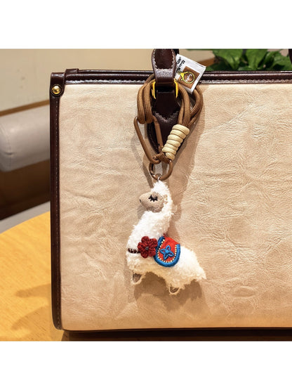 Alpaca charm keychain displayed with other colorful keychains on a hook