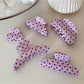 Beau pink polka dot hair clip held in hand showing size and detail