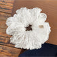 White polka dot tulle scrunchie displayed on a wooden surface