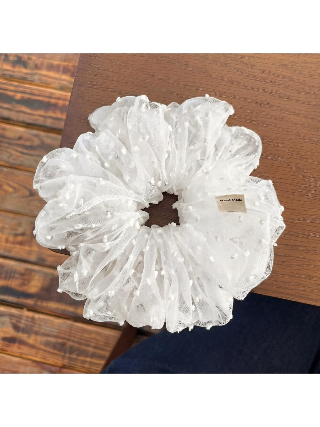 White polka dot tulle scrunchie displayed on a wooden surface
