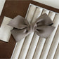 Beau solid satin bow hair clip placed on a wooden surface