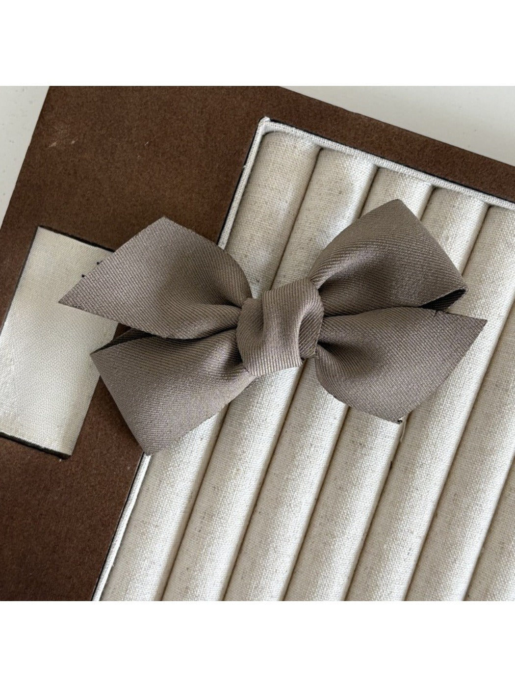 Beau solid satin bow hair clip placed on a wooden surface