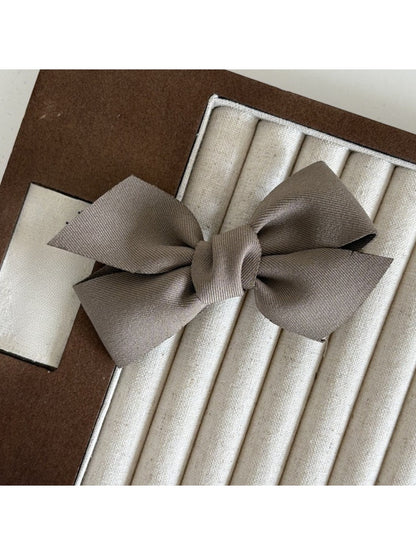 Beau solid satin bow hair clip placed on a wooden surface