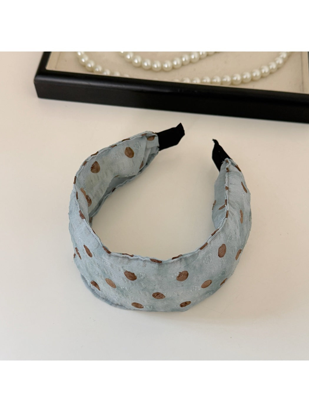 Flat lay of blue polka dot headband and scrunchie with gift box
