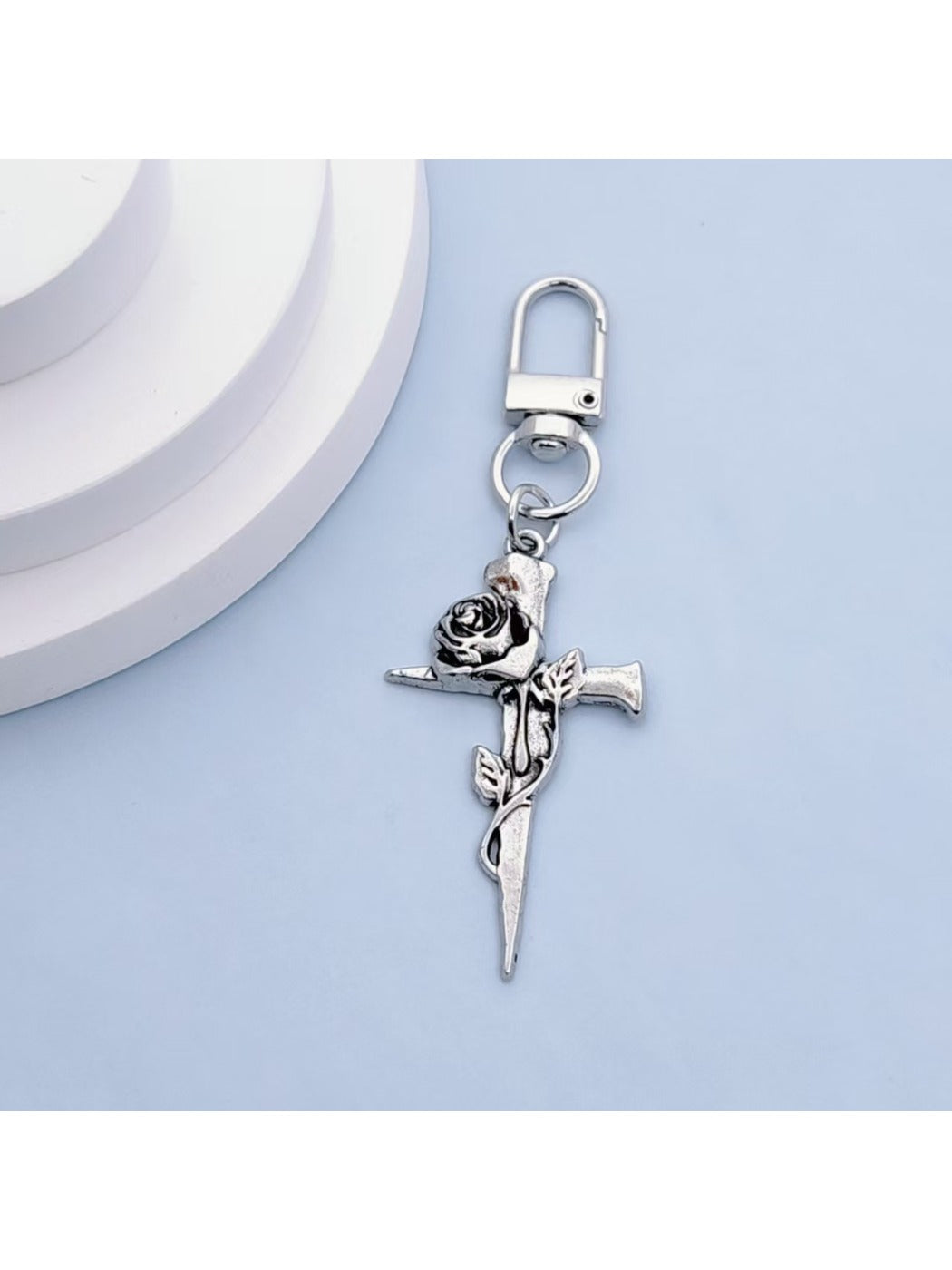 Rose gold cross keychain displayed on a black velvet pouch