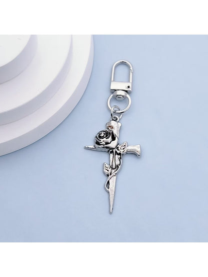 Rose gold cross keychain displayed on a black velvet pouch