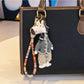 Giraffe charm keychain next to a small plant for scale