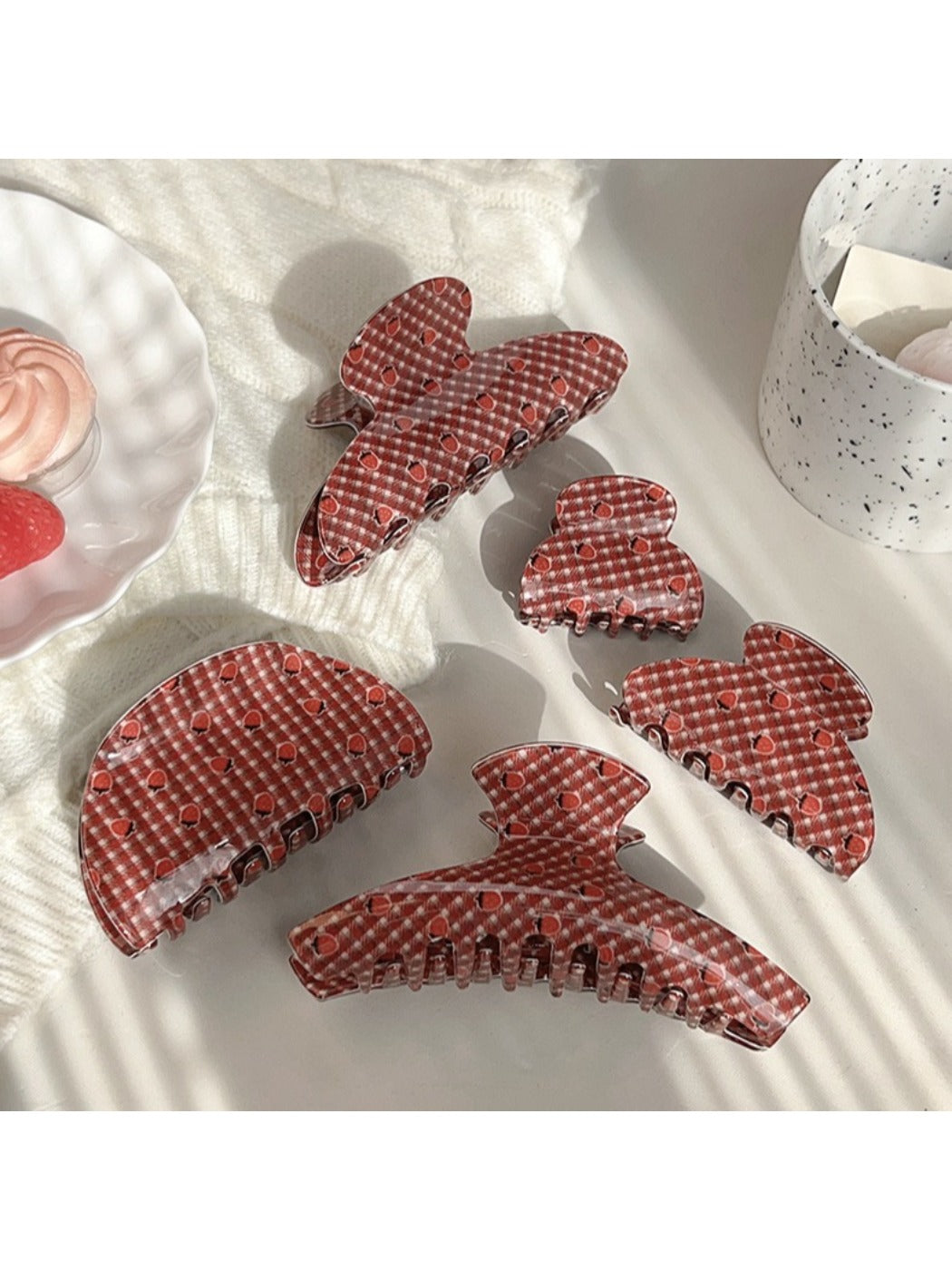 Close-up of Beau hair claw clip showing red strawberries on plaid background