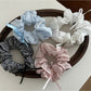 Close-up of Gifty Sweet Bow Stripe Scrunchie with pink and white stripes on a white background