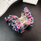 Beau double layer hollow bow shaped claw clip placed on wooden surface