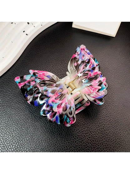 Beau double layer hollow bow shaped claw clip placed on wooden surface