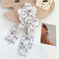 Flat lay of Gifty ruffled floral scrunchie with bow on a wooden surface