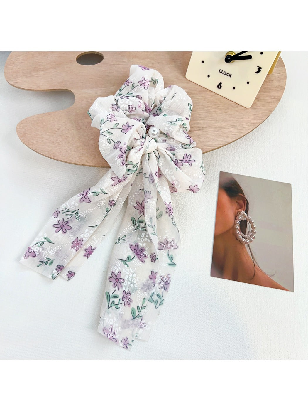 Flat lay of Gifty ruffled floral scrunchie with bow on a wooden surface