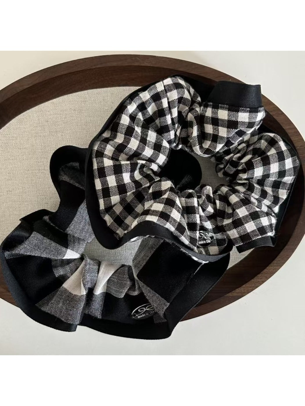 Black and white check scrunchie displayed on a wooden surface