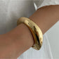Lovra wide round bangle bracelet resting on a neutral surface with natural lighting