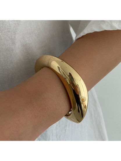 Lovra wide round bangle bracelet resting on a neutral surface with natural lighting