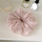 Scrunchie placed on a wooden surface emphasizing its soft material