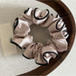 Gifty satin scrunchie in pink shown alongside other hair accessories on a table