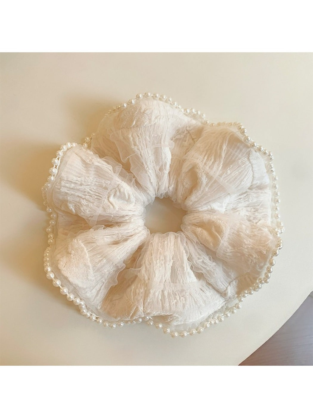 Soft fabric beige scrunchie with ruffled edges in natural light