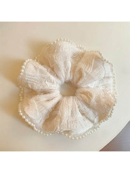 Soft fabric beige scrunchie with ruffled edges in natural light