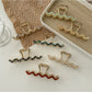 Beau wavy metal claw clip in gold on white background