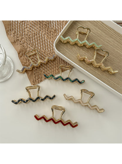 Beau wavy metal claw clip in gold on white background