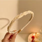 Close-up of hand holding delicate gold wire headband with tiny white beads