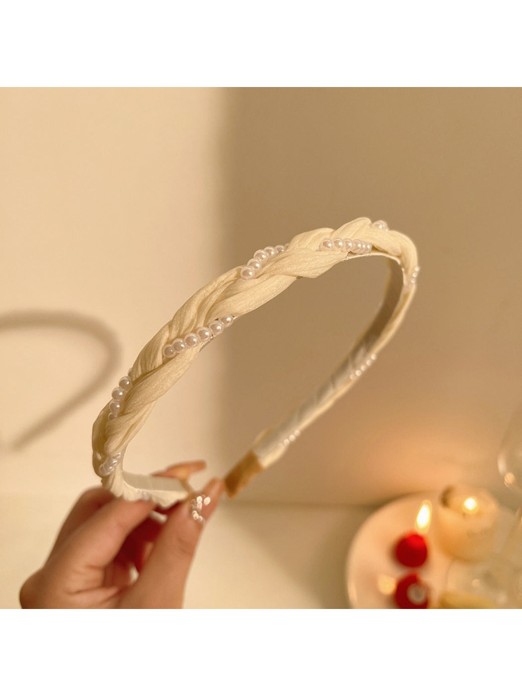 Close-up of hand holding delicate gold wire headband with tiny white beads