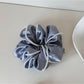 Multiple Gifty satin scrunchies in various colors displayed on a white surface
